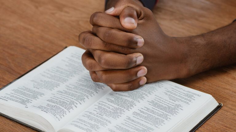 Praying hands near a bible