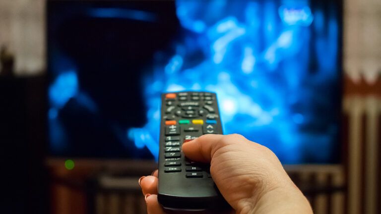 Hand pointing remote control towards TV