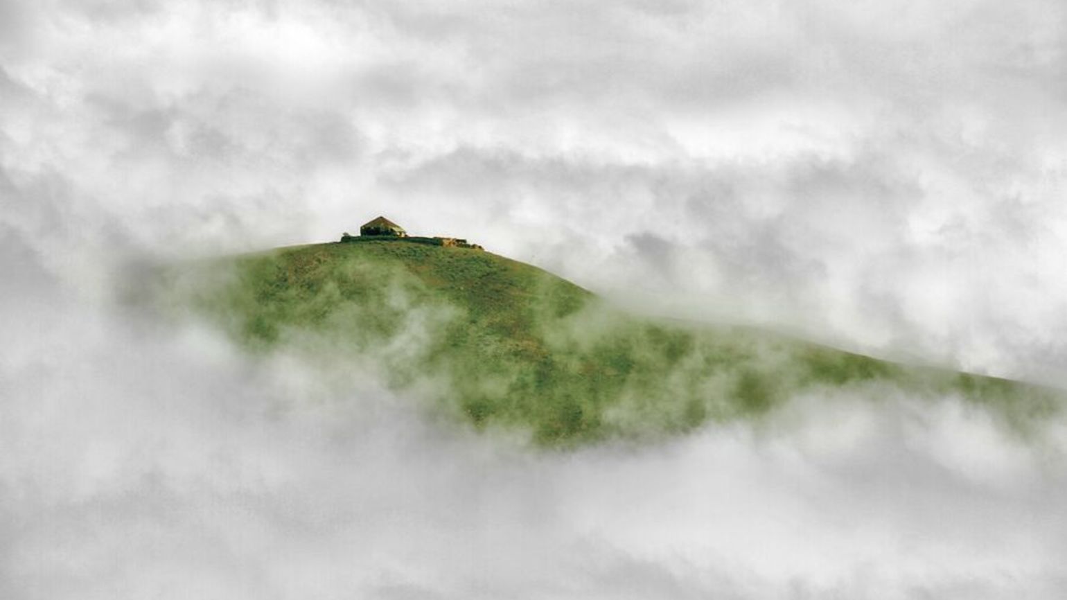 Green hill peaking through clouds doing positive living with an inspirational quote