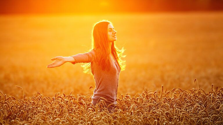 Woman standing in a wheat field with open arms