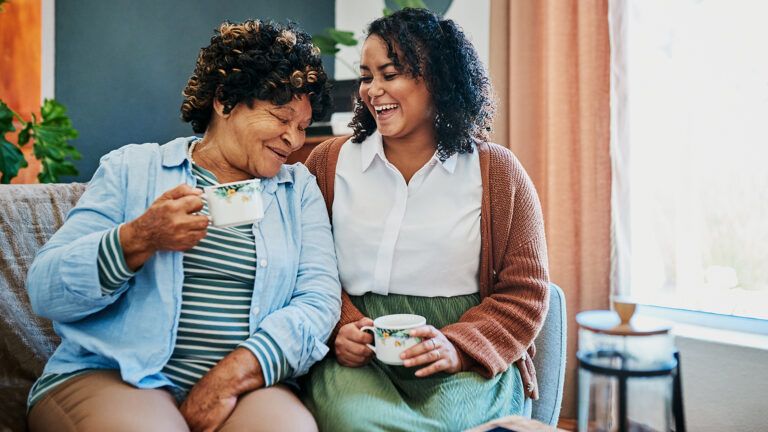 Adult daughter and senior mother having tea together