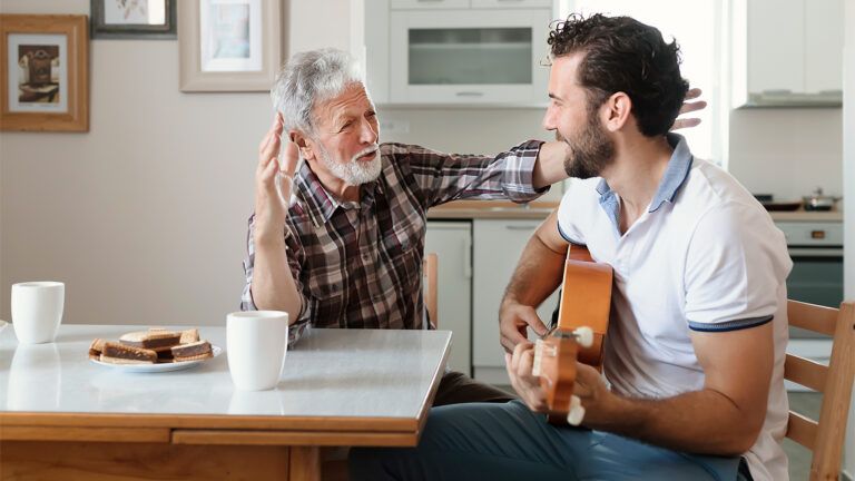 An adult son plays the guitar for his father with Alzheimer's; Getty Images