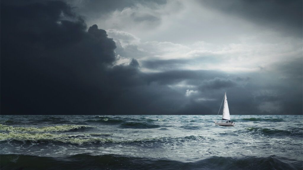 A lonely white sailboat in stormy waters; credit: Getty Images