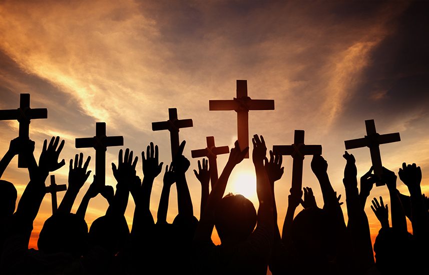 Group of hands holding up crosses