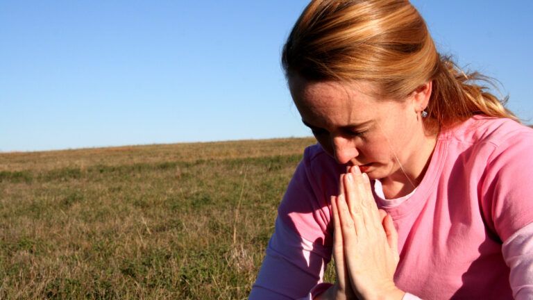 A woman bows her head in prayer