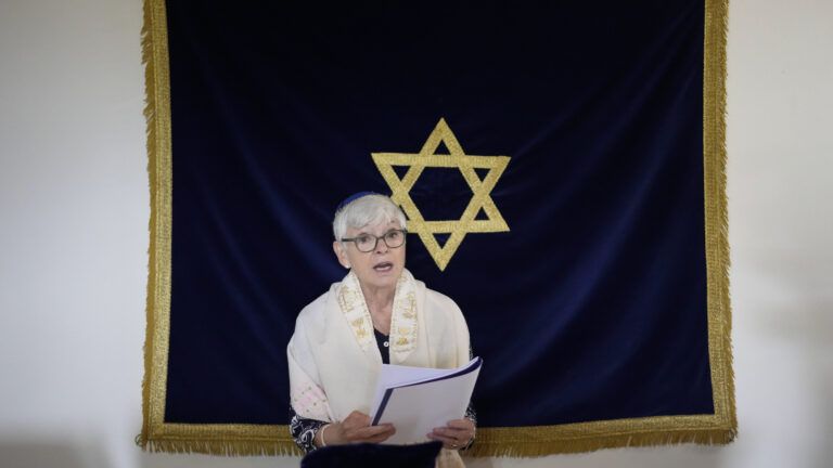 Rabbi Barbara Aiello reads prayers in her synagogue in her story of faith