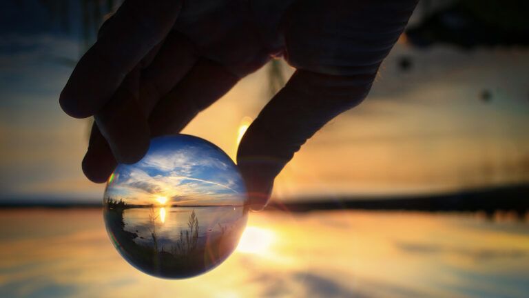 Transparent glass ball reflecting a sunset on the lake