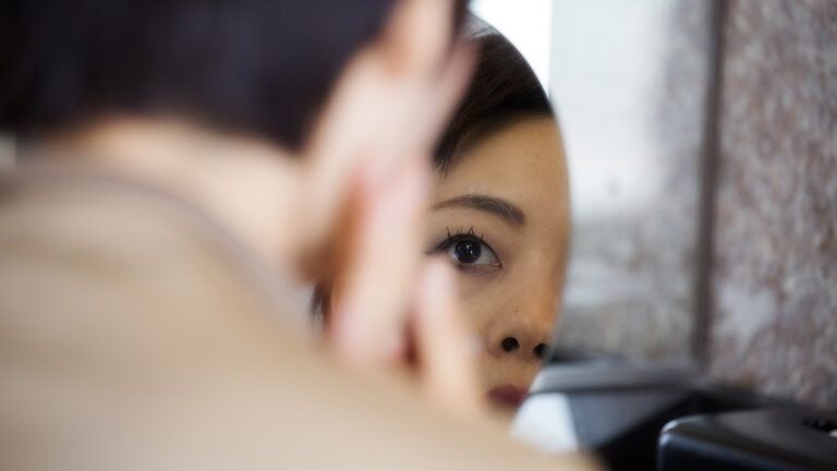 A woman gazes into a mirror
