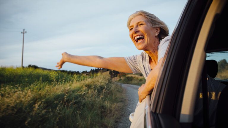 Woman smiling out a car window regaining childlike wonder as an adult