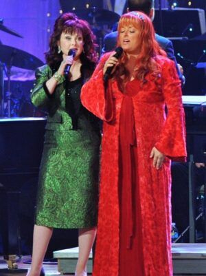 Wynonna and Naomi Judd sing onstage together in their story of faith