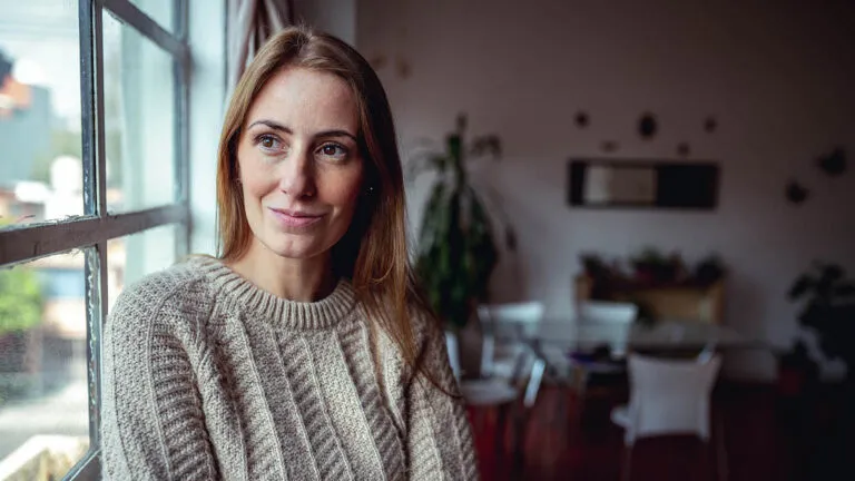 Woman looking at herself in the mirror thanking about gratitude vs thankfulness