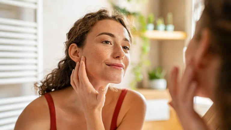 Woman looking at herself in the mirror thanking about gratitude vs thankfulness