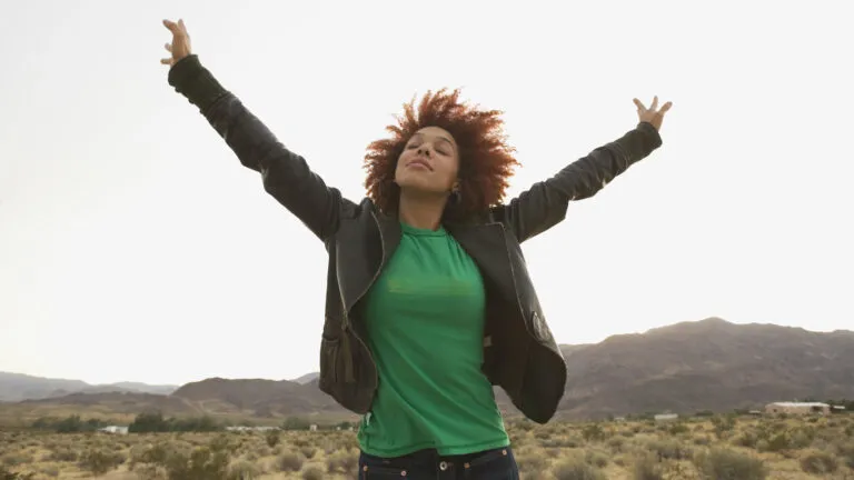 Woman outside with her arms raised saying a short prayer for gratitude