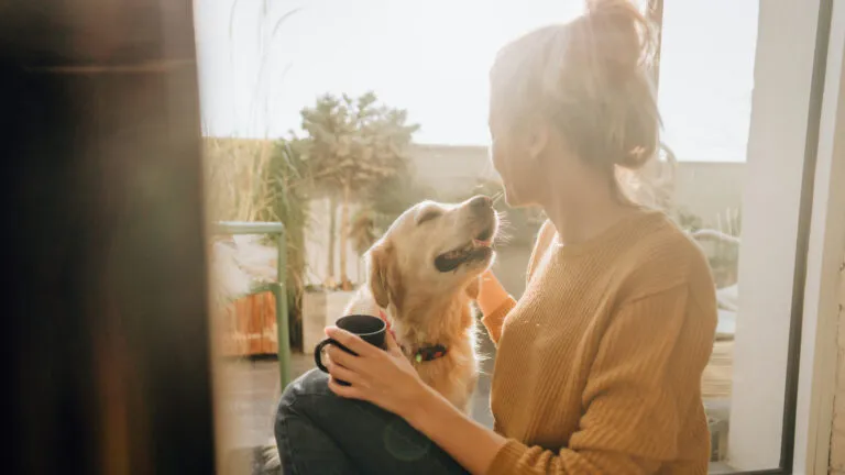 Woman petting her dog in the morning and saying a prayer of gratitude