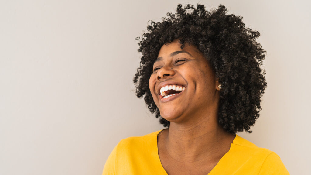 A smiling woman in a yellow shirt feeling joyful about the advent themes