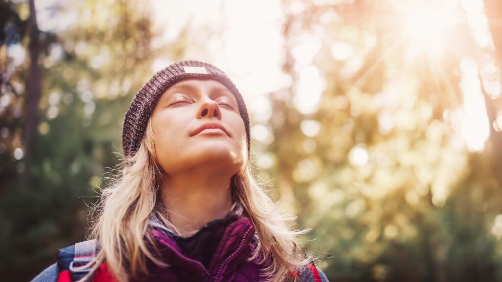A woman with her eyes closed outside in nature thinking about the four advent themes