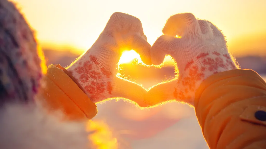 Gloved hands making a heart symbol for the advent theme of love