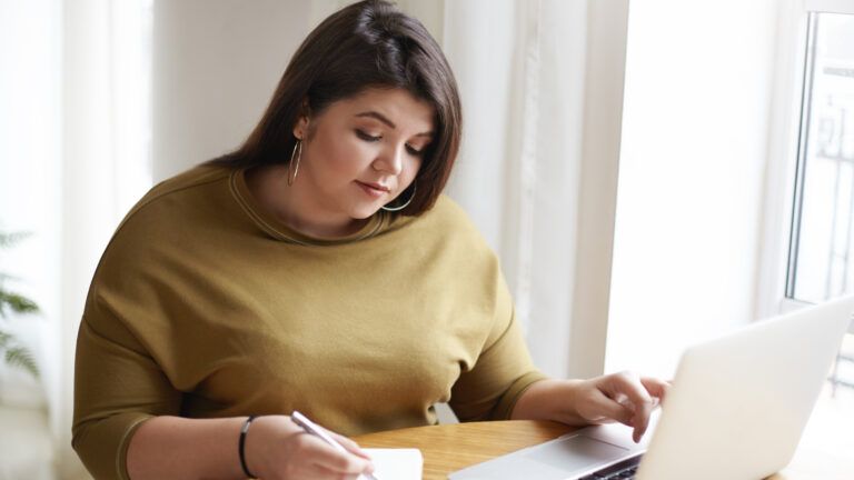 Woman writing her new year new habits in a journal at her desk
