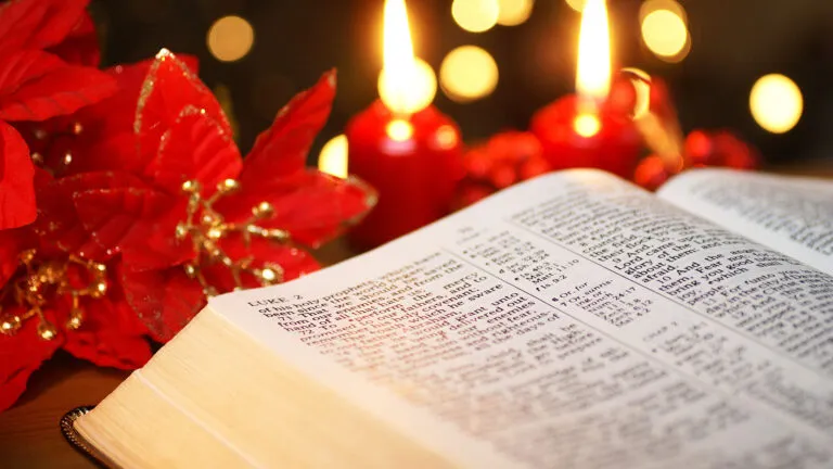 An open Bible and a pair of lit Advent candles