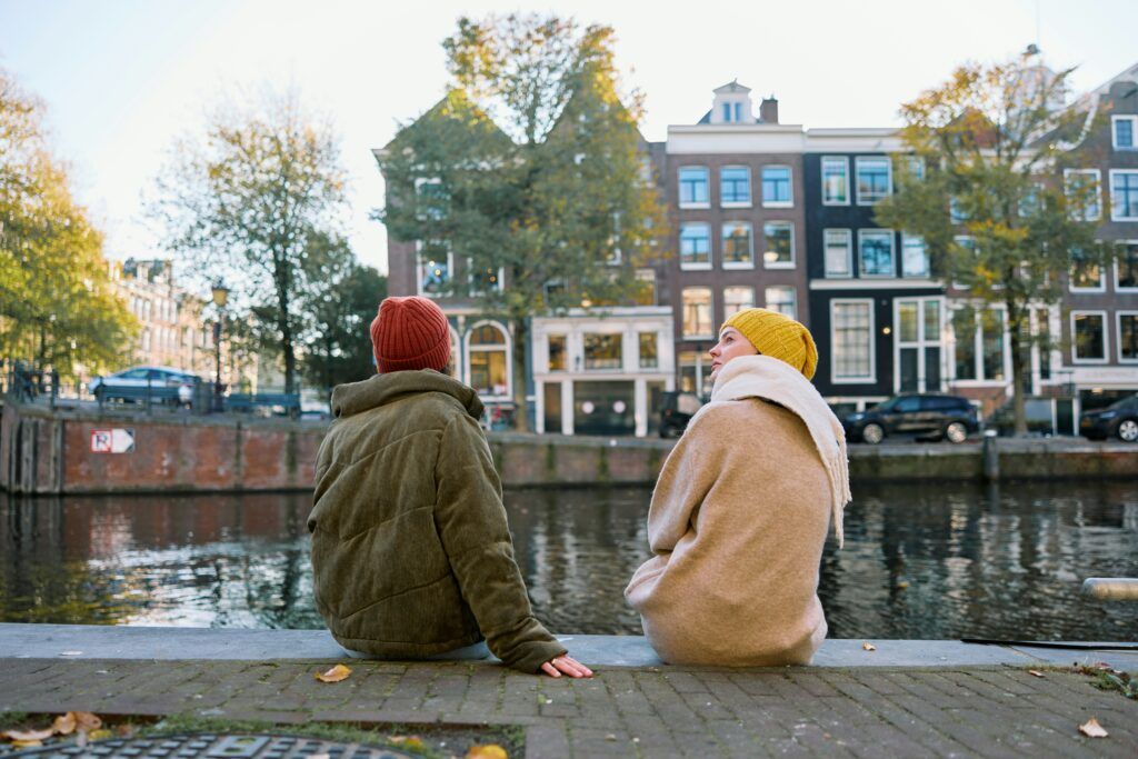 Two people sitting on a ledge overlooking a body of water.