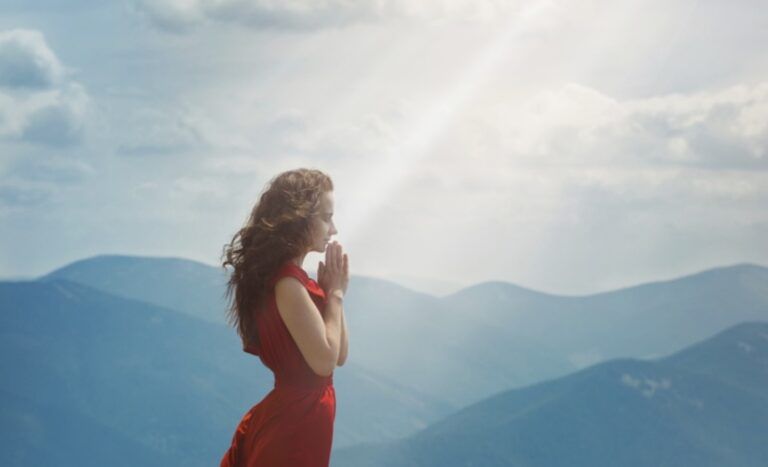 Woman praying in mountain landscape