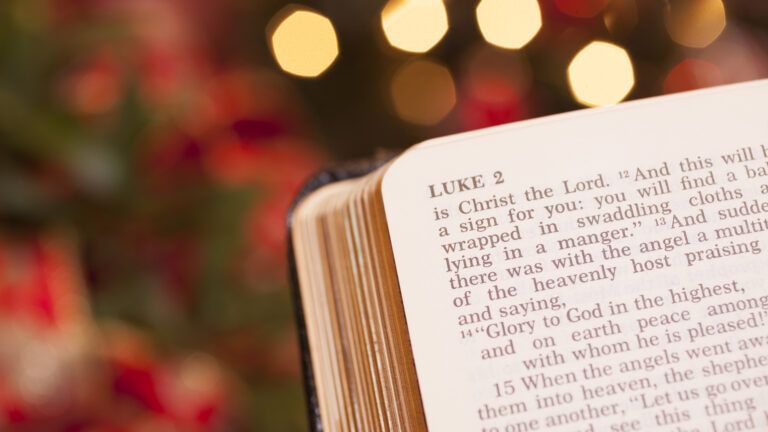 Bible showing the Christmas origin in the Book of Luke in front of Christmas lights