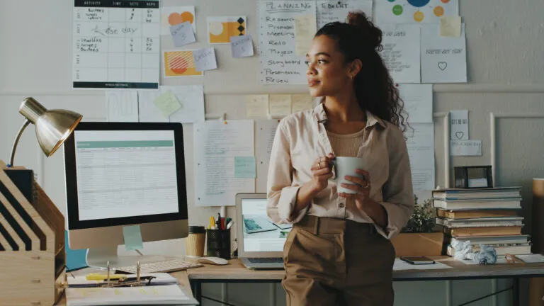 Businesswoman at her desk with a cup of coffee doing a micro habit for work