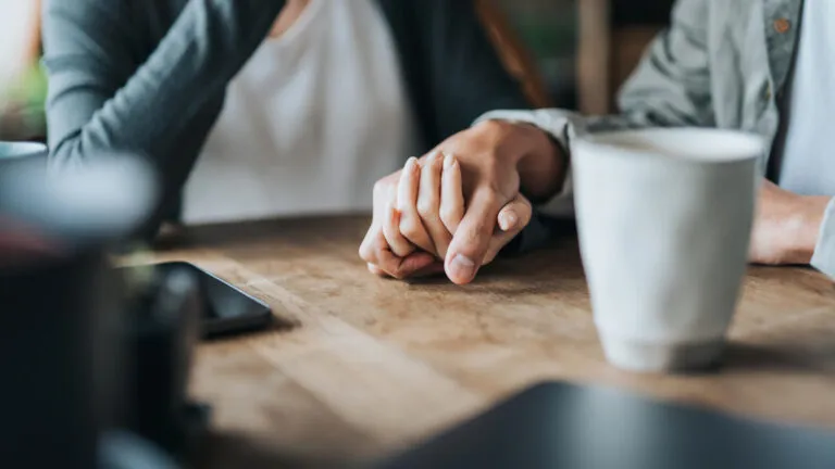 Couple holding hands at a cafe for their marriage habit