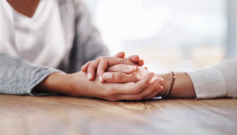 Person holding another person's hands for their comforting bible habits