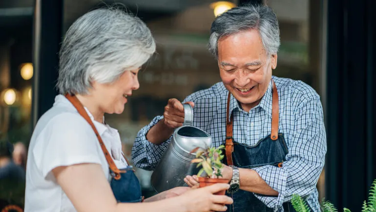 Senior couple watering plants together for their marriage habit