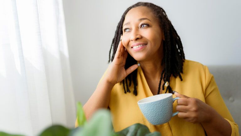 A smiling woman with a cup of coffee starts her new year habits