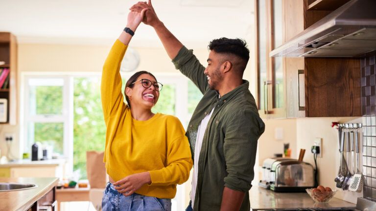 Young couple dancing in their kitchen after doing a micro habit for happiness