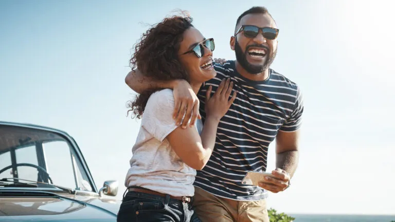 Young couple on their car laughing for their marriage habit