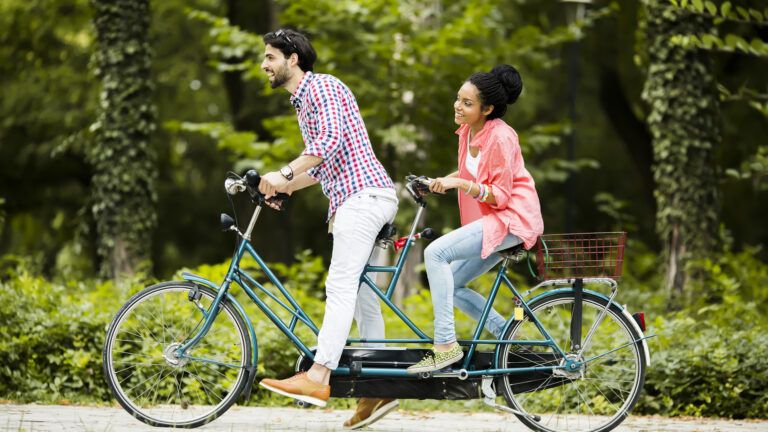Young couple riding a tandem bike outside to increase joy in marriage