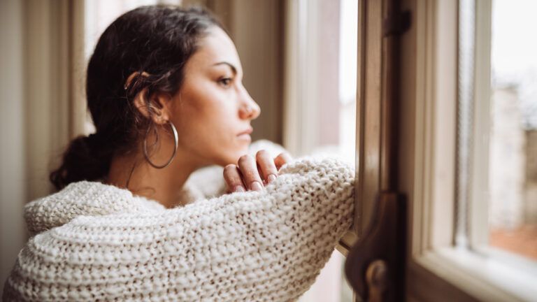 Pensive woman staring out the window; Getty Images