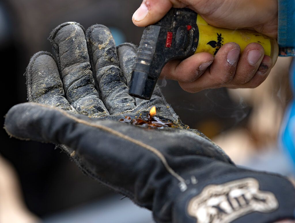 A bull rider melts rosin on his glove; photo by Wade Payne