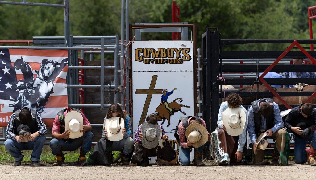Young cowboys kneel in prayer; photo by Wade Payne