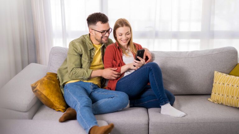 Couple with faith in their marriage on the couch looking at a phone together