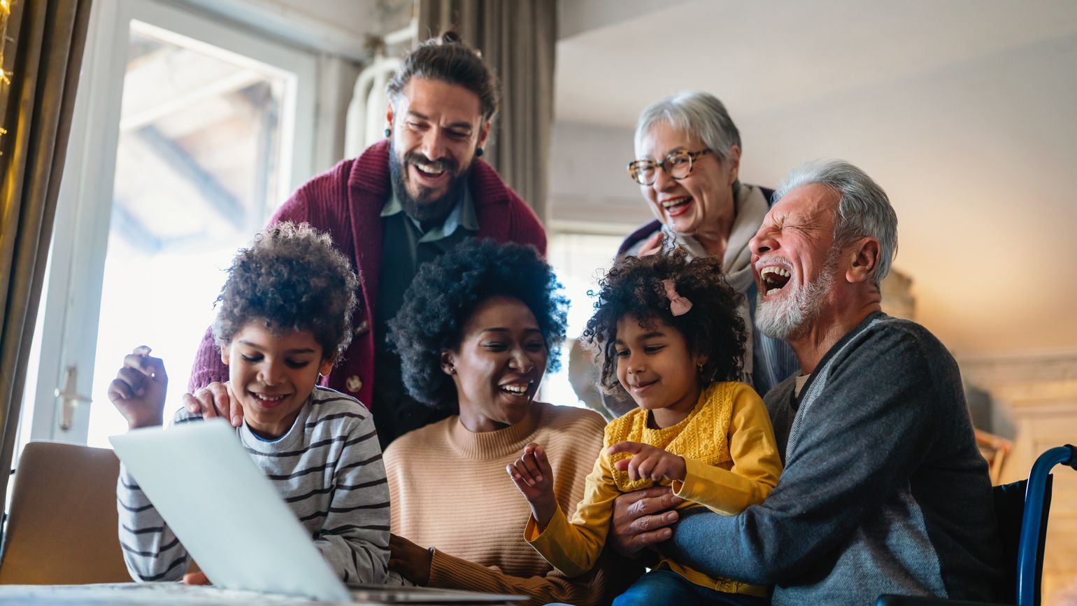 Family laughing together while looking at a computer with Bible verses about love