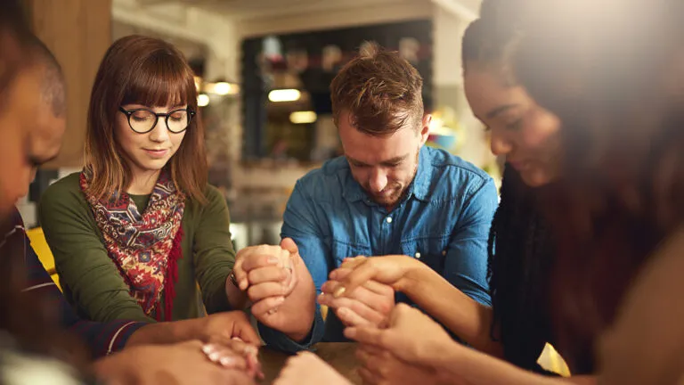 Group of young people praying effectively together