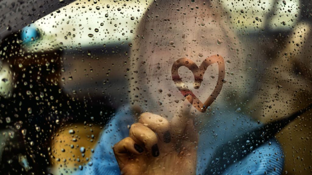 Person drawing a heart shape on the window to signify god's love