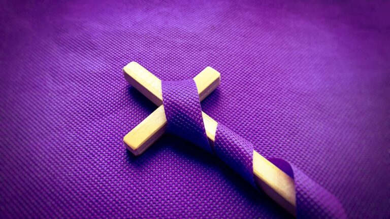 Purple ribbon in the colors of lent wrapped around a wooden cross