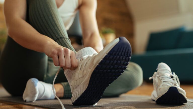 Woman putting on a sneaker to exercise for her new habits