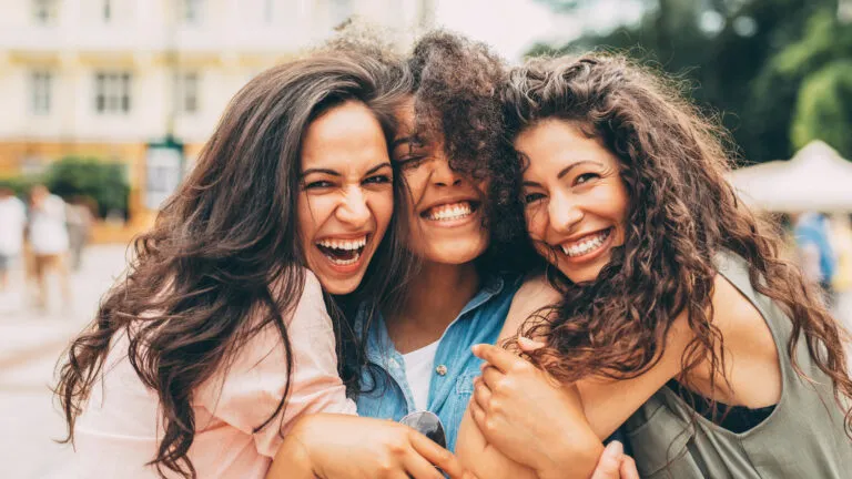 Three girl friends hugging each other outside to show Bible verses about love