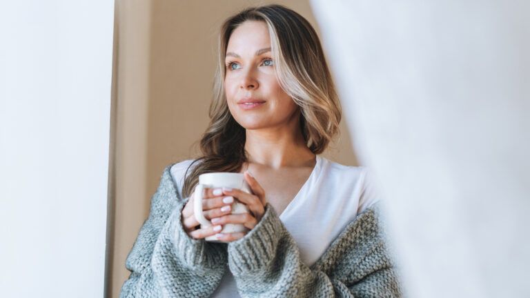 Peaceful woman holding cup of coffee and thinking about spiritual balance