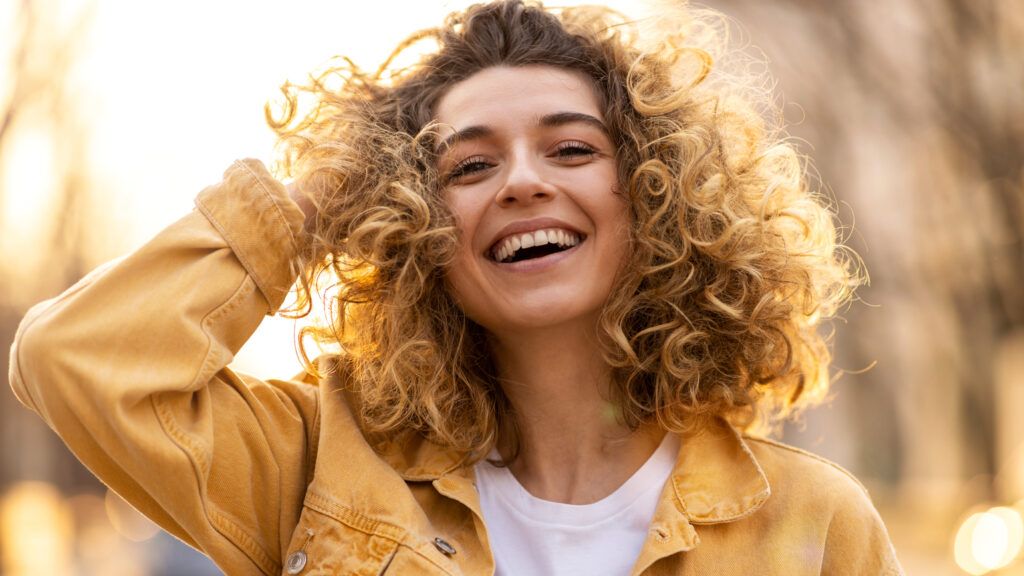 Woman in a yellow jacket smiling while feeling God's love for her