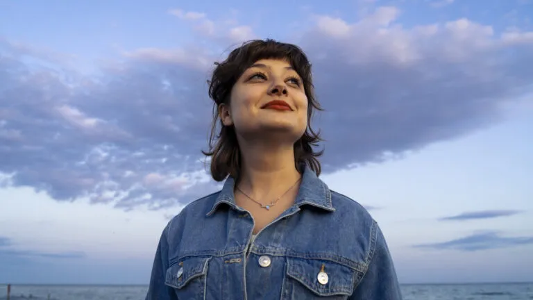 Woman in the denim jacket looking to the sky for bible verses about the love of God