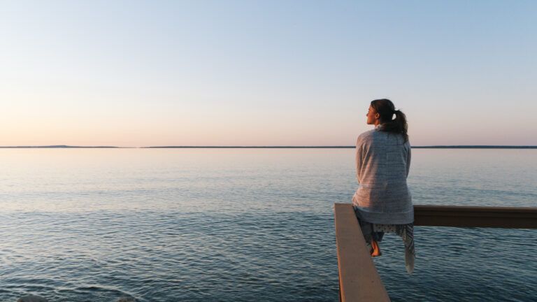 Woman sitting alone on a dock by the sea for her new years habit
