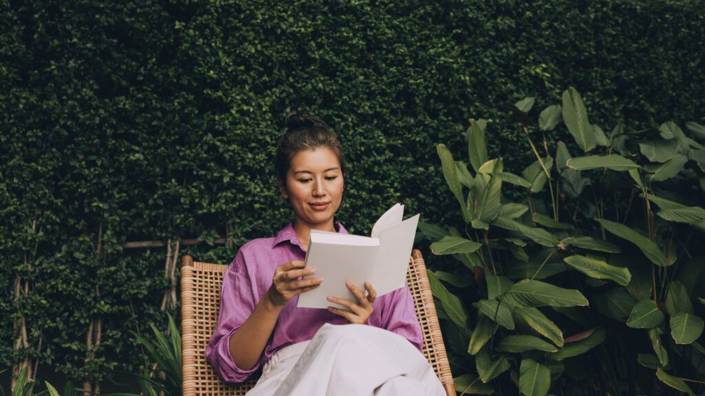 Woman sitting in her garden reading a book with Lent quotes
