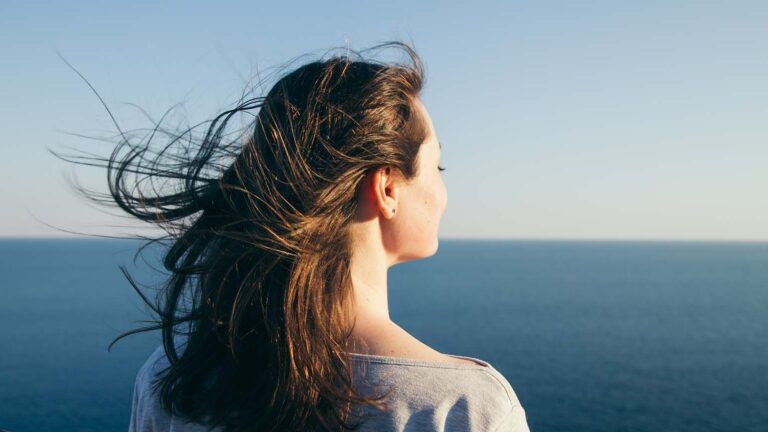 Woman staring at the ocean to reflect on the blue colors of lent